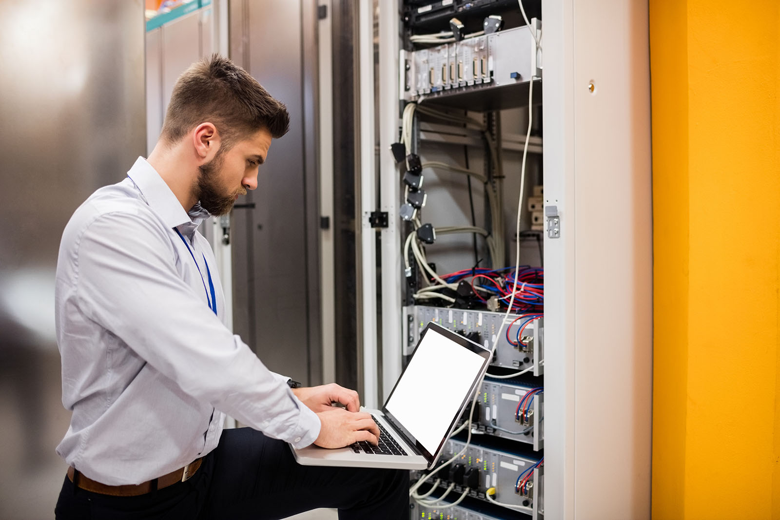 Technician,Using,Laptop,While,Analyzing,Server,In,Server,Room